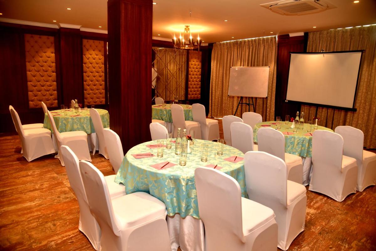 a conference room with tables and white chairs and a screen at The Orchid Shimla in Shimla