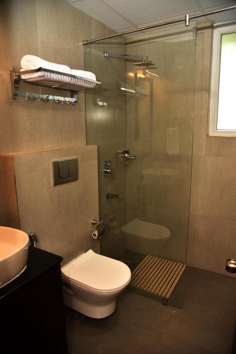 a bathroom with a shower and a toilet and a sink at The Orchid Shimla in Shimla