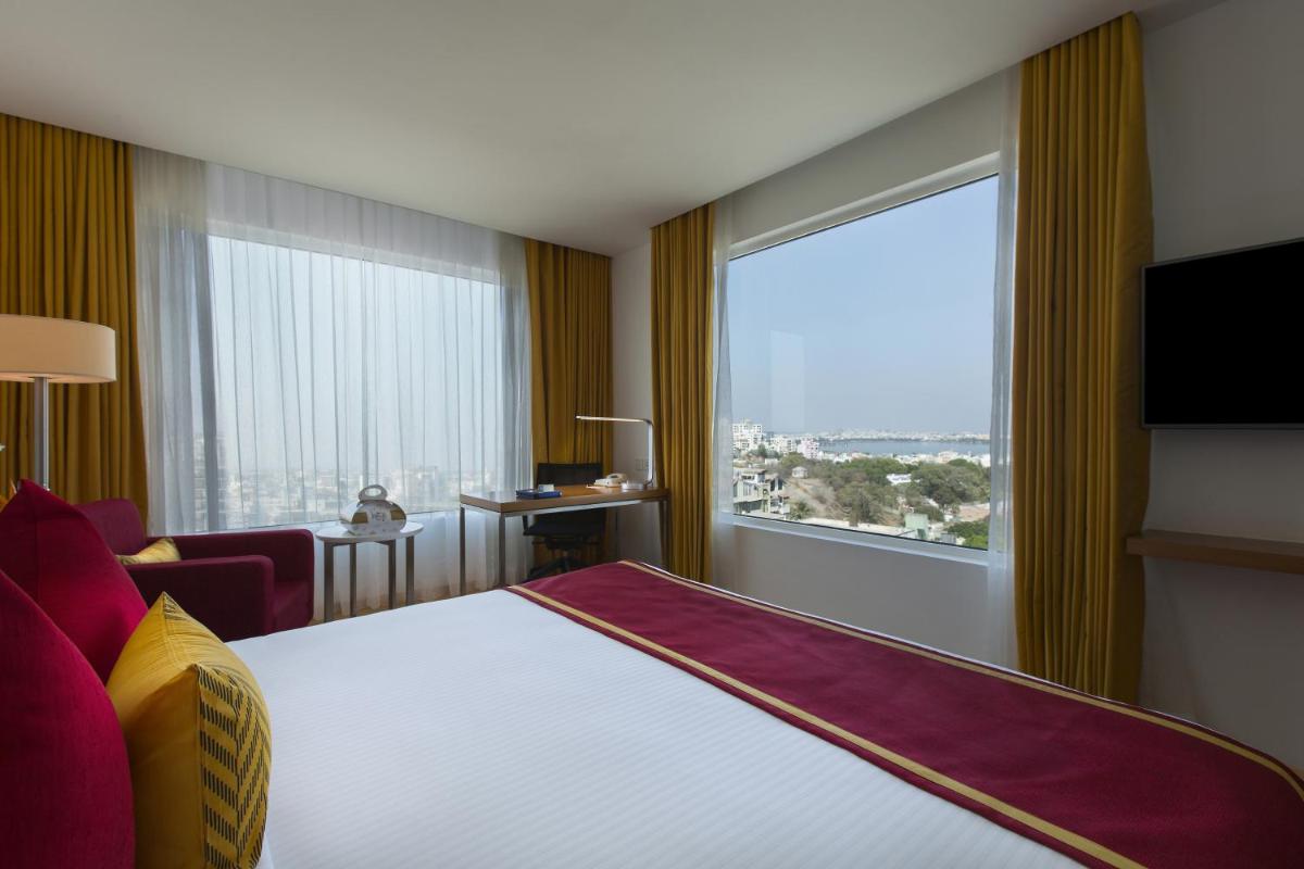 a hotel room with a bed and a large window at Mercure Hyderabad KCP Banjara Hills, An Accor Hotel in Hyderabad a hotel room with a bed and a large window at Mercure Hyderabad KCP Banjara Hills, An Accor Hotel in Hyderabad