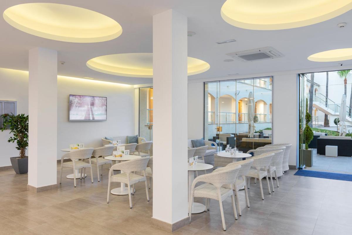 un restaurante con mesas blancas y sillas blancas en Trendhotel Alcudia - Adults Only, en Puerto de Alcudia