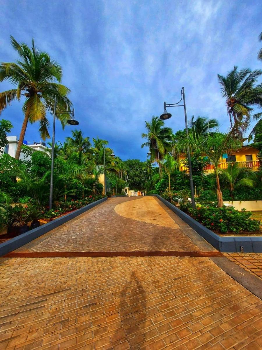 a woman walking down a brick road with palm trees at Holiday Inn Goa Candolim in Candolim a woman walking down a brick road with palm trees at Holiday Inn Goa Candolim in Candolim