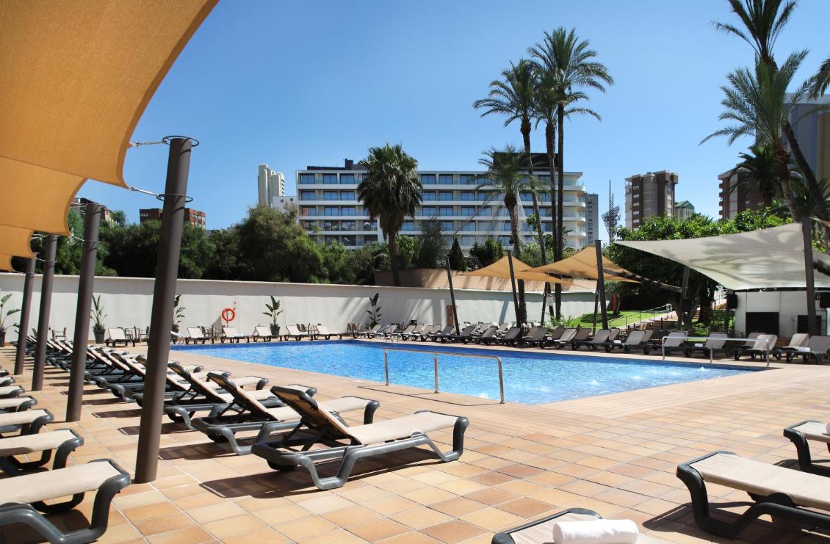 una piscina con tumbonas junto a un complejo en Helios Benidorm, en Benidorm