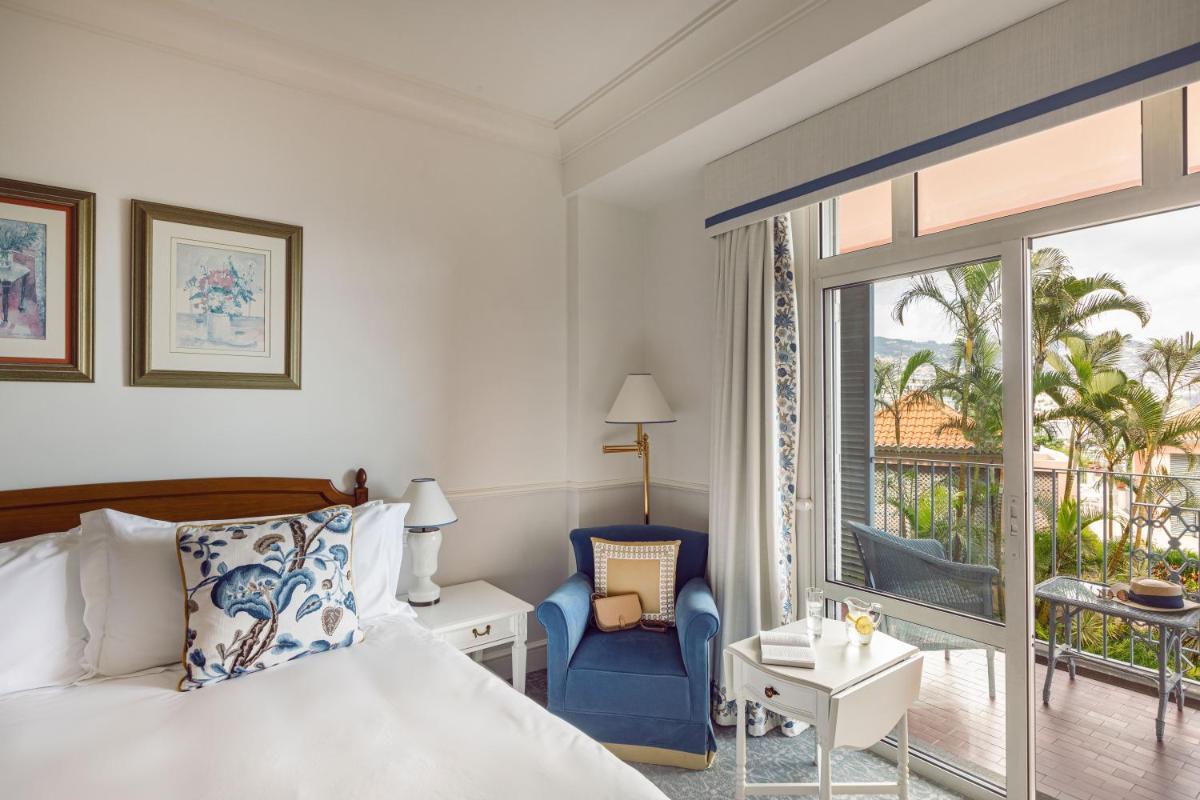 um quarto de hotel com uma cama e uma varanda em Reid's Palace, A Belmond Hotel, Madeira no Funchal