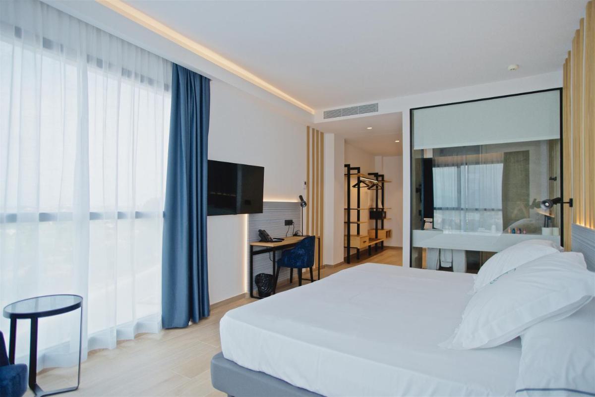 Un dormitorio con una cama blanca y una ventana grande. en Syncrosfera Fitness & Spa Health Hotel Boutique, en Pedreguer