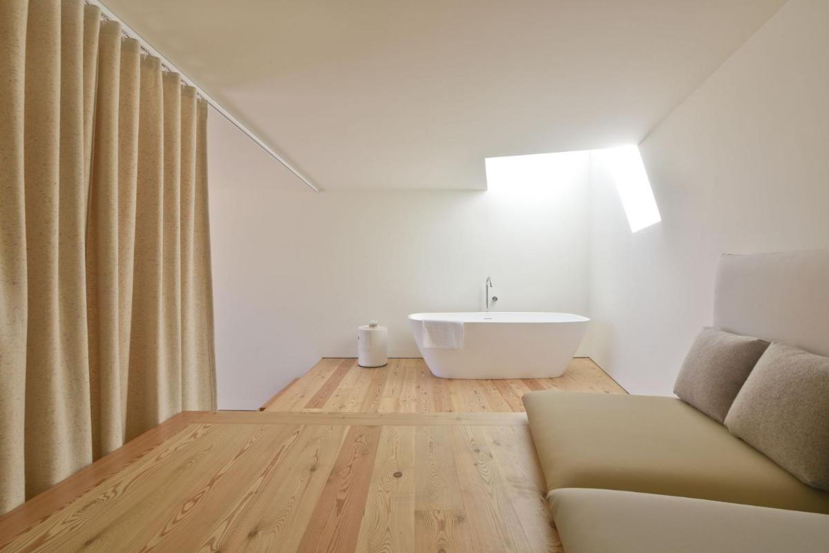 uma casa de banho com um lavatório e um sofá em Casas Da Lapa, Nature & Spa Hotel em Seia