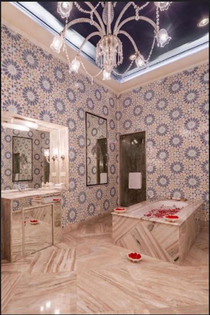 a bathroom with a chandelier and a sink and a mirror at Rajmahal Palace RAAS in Jaipur