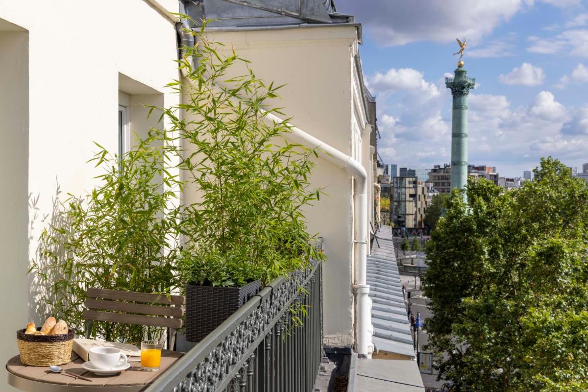 - un balcon avec une table et des plantes dans un bâtiment dans l'établissement Le Petit Beaumarchais Hotel & Spa, à Paris