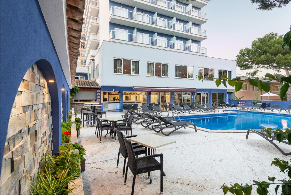un patio del hotel con mesas y sillas junto a una piscina en Hotel Torre Azul & Spa - Adults Only, en El Arenal