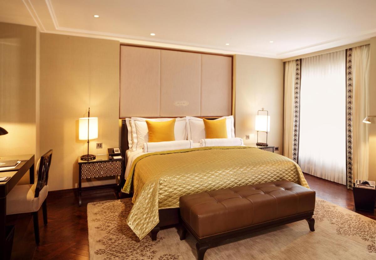 a bedroom with a large bed and a desk at The Claridges New Delhi in New Delhi a bedroom with a large bed and a desk at The Claridges New Delhi in New Delhi