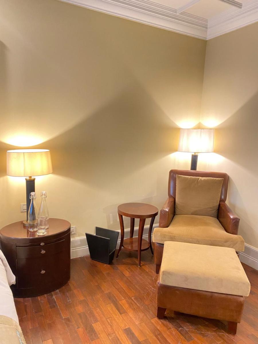 a bedroom with a bed and a chair and a table at The Claridges New Delhi in New Delhi a bedroom with a bed and a chair and a table at The Claridges New Delhi in New Delhi