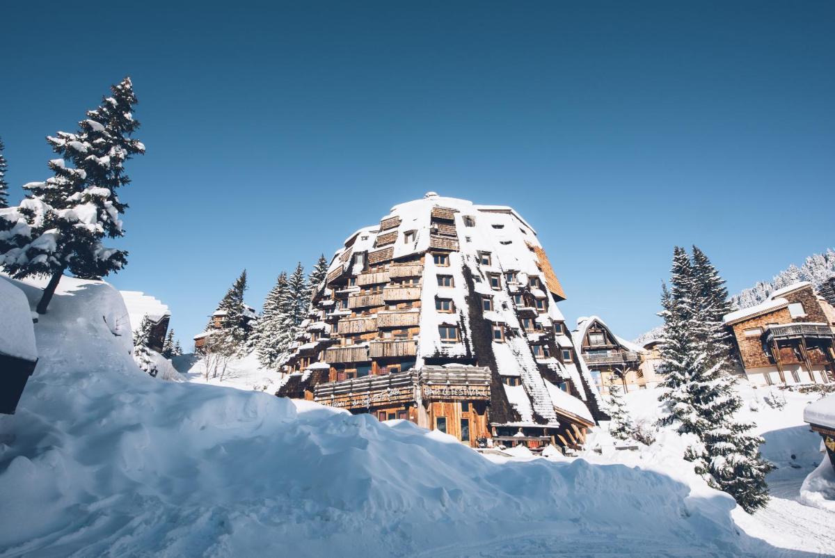 un bâtiment recouvert de neige avec un tas de neige dans l'établissement Hôtel des Dromonts by SOWELL COLLECTION, à Avoriaz
