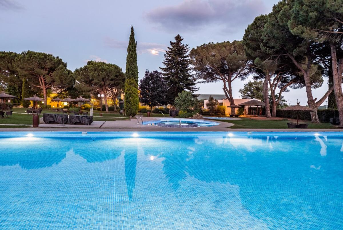 Una gran piscina azul con árboles al fondo. en Hotel Mas Solà, en Santa Coloma de Farners