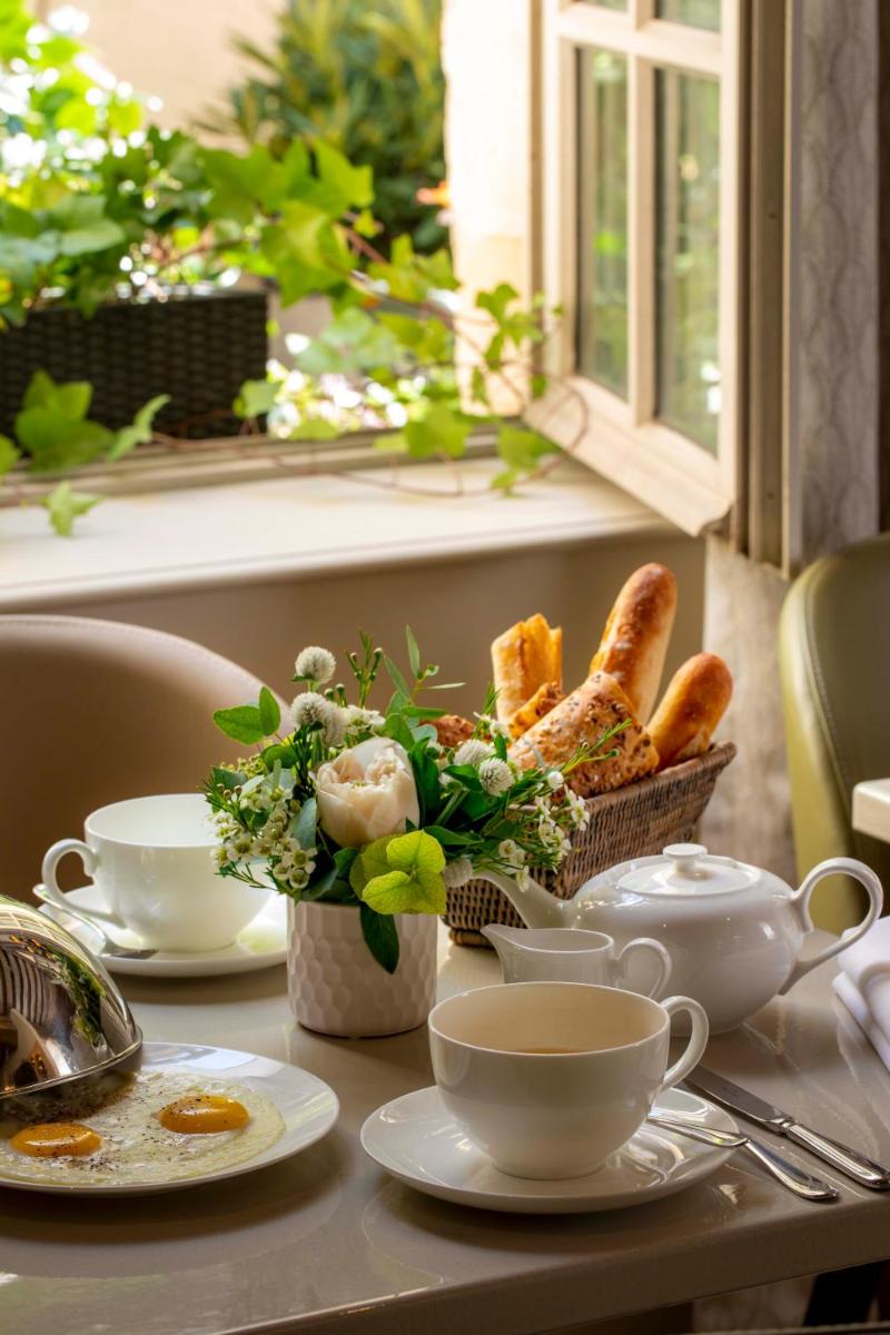 une table avec du pain, des tasses et un panier de pain dans l'établissement Hôtel D'Aubusson, à Paris