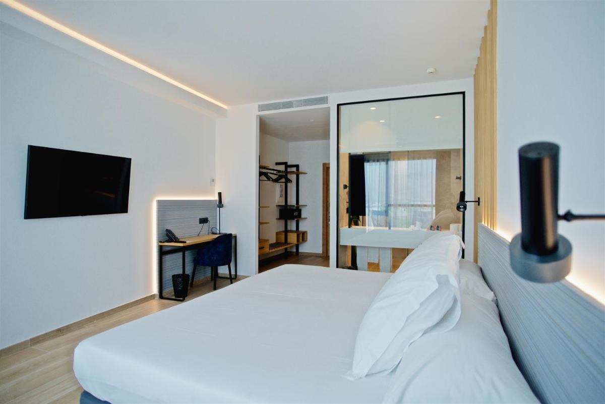 Un dormitorio con una cama blanca y un televisor. en Syncrosfera Fitness & Spa Health Hotel Boutique, en Pedreguer 70 fotos más