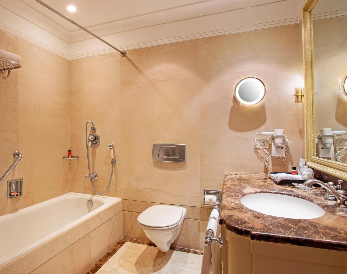 a bathroom with a sink and a tub and a toilet at The Claridges New Delhi in New Delhi a bathroom with a sink and a tub and a toilet at The Claridges New Delhi in New Delhi