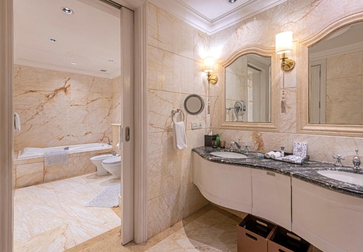 a bathroom with two sinks and a tub and a toilet at The Claridges New Delhi in New Delhi a bathroom with two sinks and a tub and a toilet at The Claridges New Delhi in New Delhi