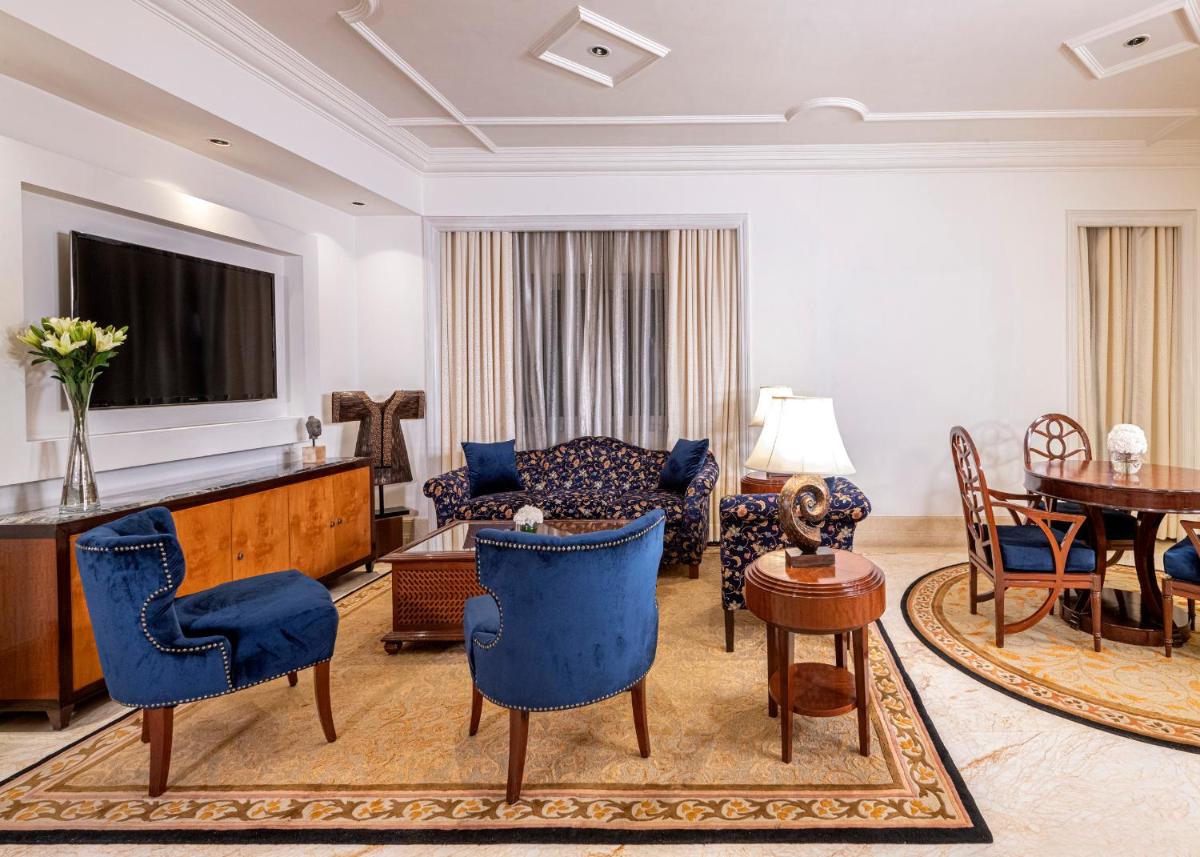 a living room with blue chairs and a couch at The Claridges New Delhi in New Delhi a living room with blue chairs and a couch at The Claridges New Delhi in New Delhi