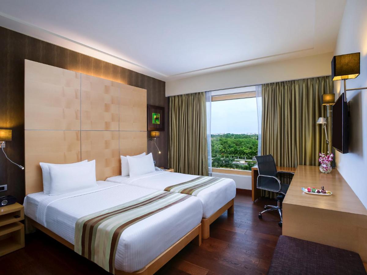 a hotel room with a large bed and a desk at Novotel Hyderabad Airport in Hyderabad