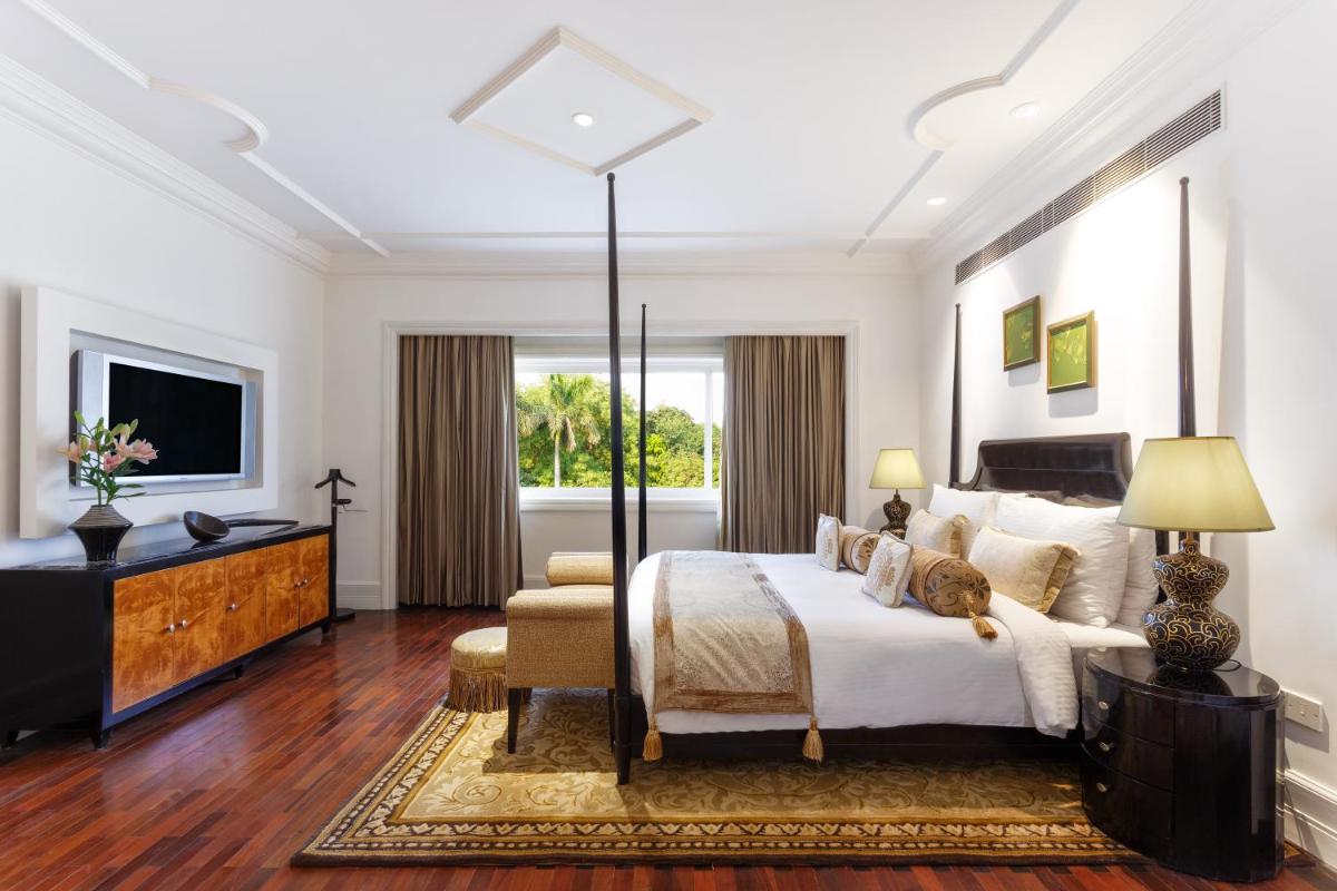 a bedroom with a large bed and a television at The Claridges New Delhi in New Delhi a bedroom with a large bed and a television at The Claridges New Delhi in New Delhi