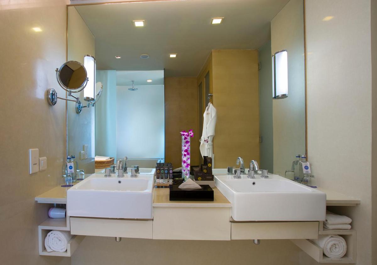 a bathroom with two sinks and a large mirror at Novotel Hyderabad Airport in Hyderabad