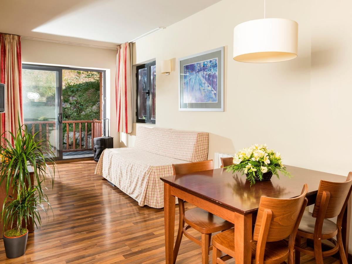 Una sala de estar con una mesa y una cama. en Guitart La Molina Aparthotel & Spa, en La Molina Una sala de estar con una mesa y una cama. en Guitart La Molina Aparthotel & Spa, en La Molina