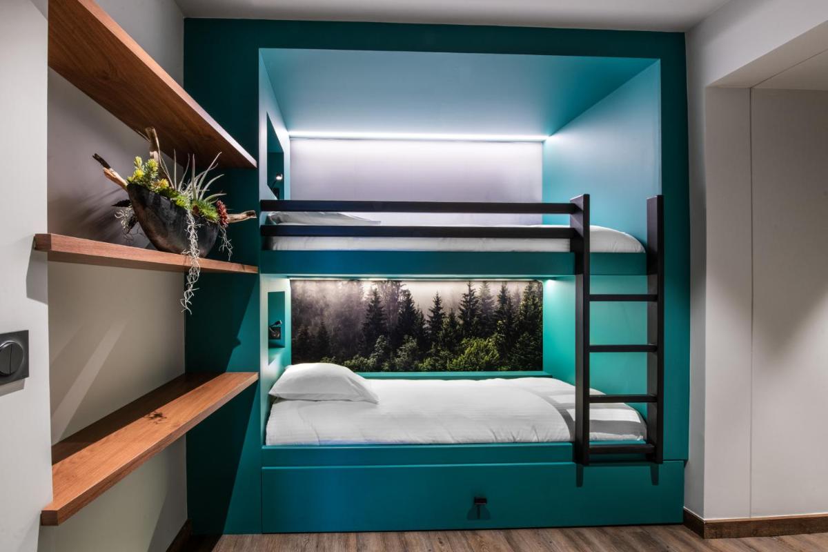 Ce lit superposé se trouve dans un dortoir doté d'un mur bleu. dans l'établissement L'Arcalod & Bistrot Jeanne - Lac d'Annecy - Hôtel Restaurant Spa, à Doussard