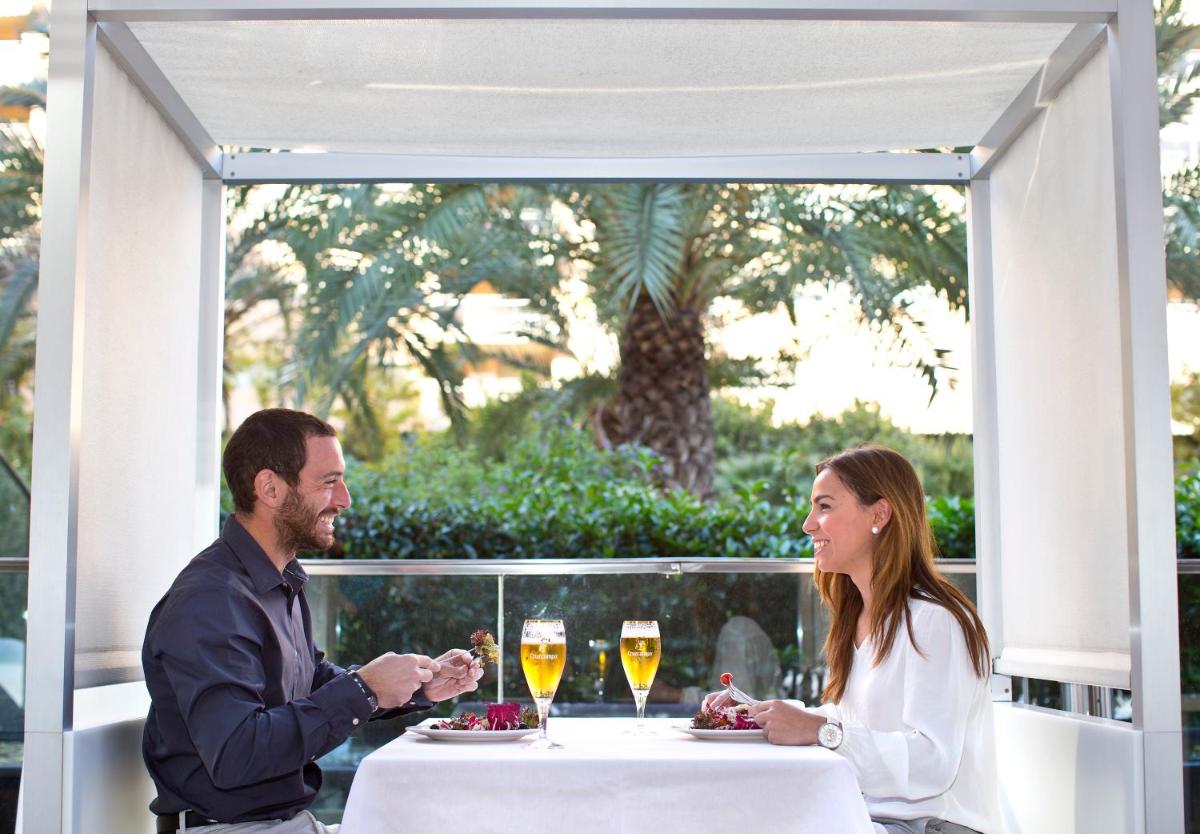 Un hombre y una mujer sentados en una mesa con copas de vino. en Primus Valencia, en Valencia