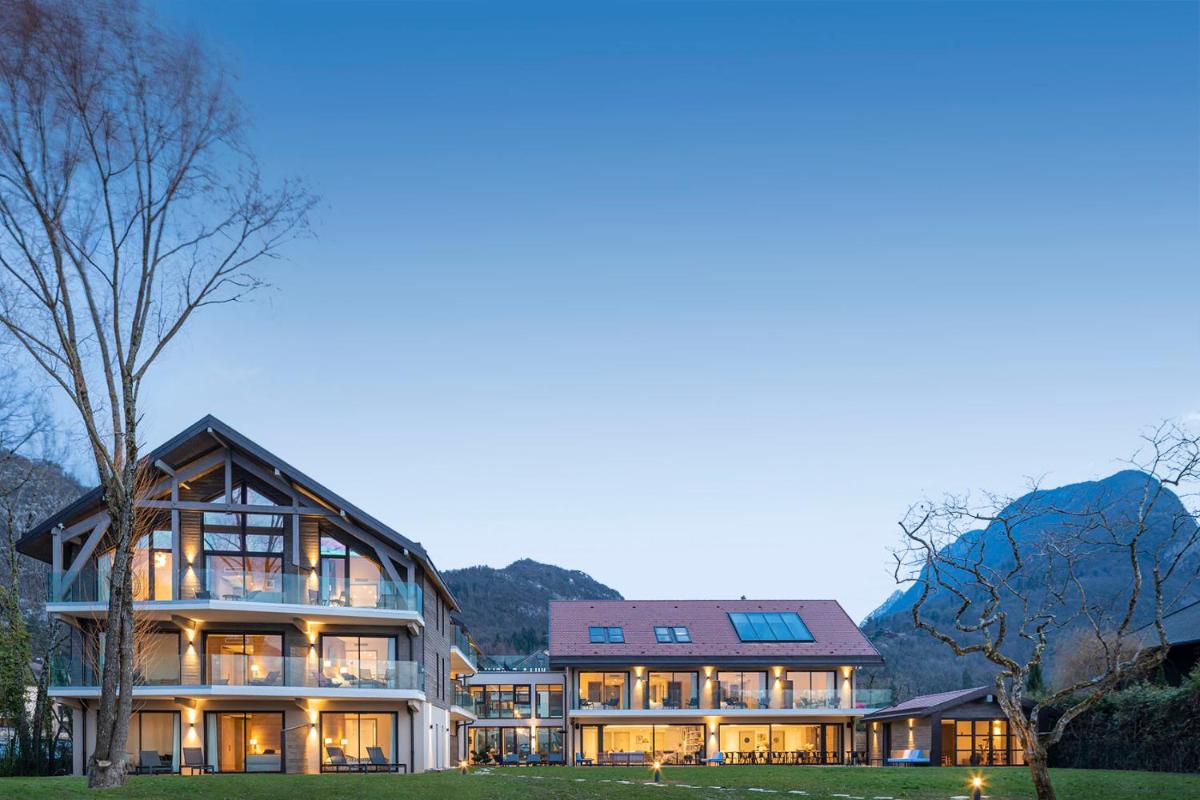 une grande maison avec de nombreuses fenêtres et un arbre dans l'établissement Villa Caroline, Lac d'Annecy, à Duingt