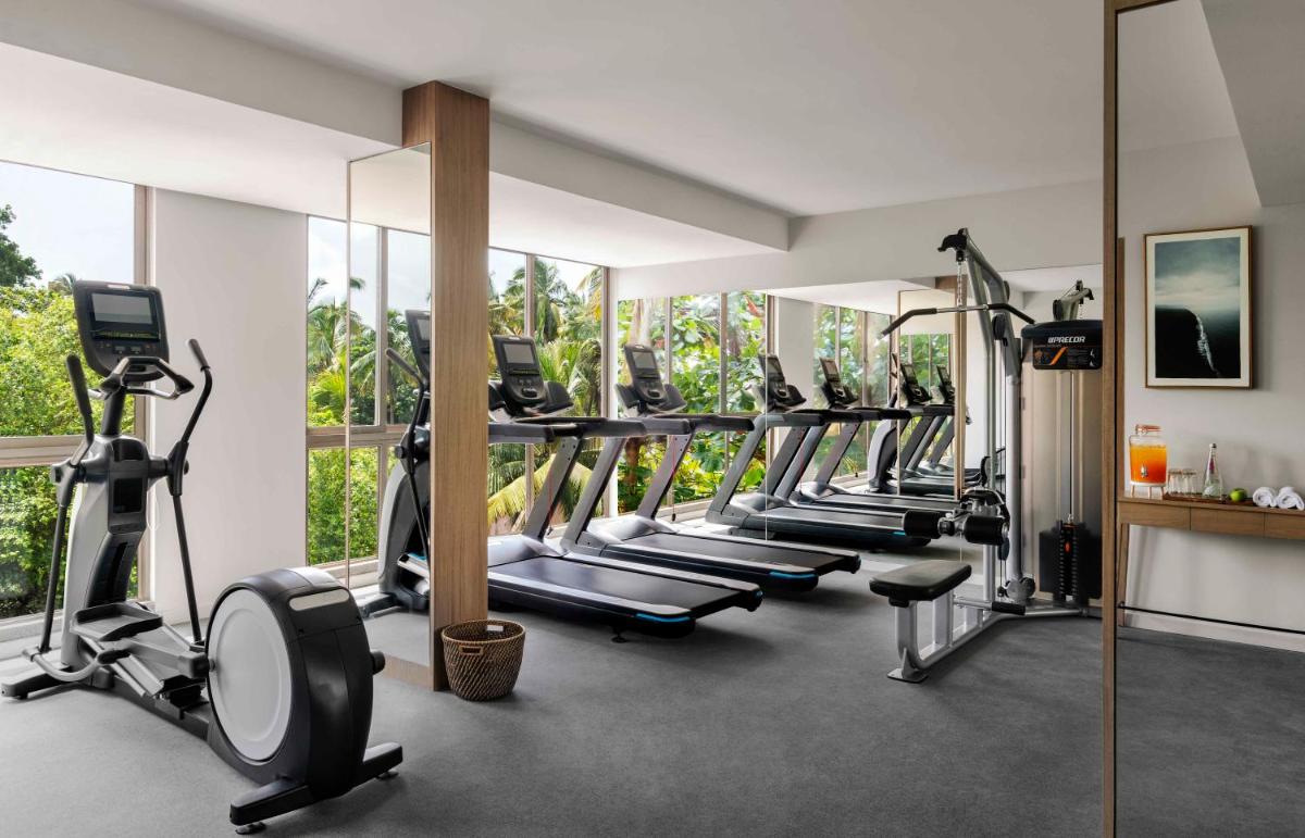 a gym with a row of treadmills and ellipticals at Vivanta Goa, Miramar in Panaji a gym with a row of treadmills and ellipticals at Vivanta Goa, Miramar in Panaji