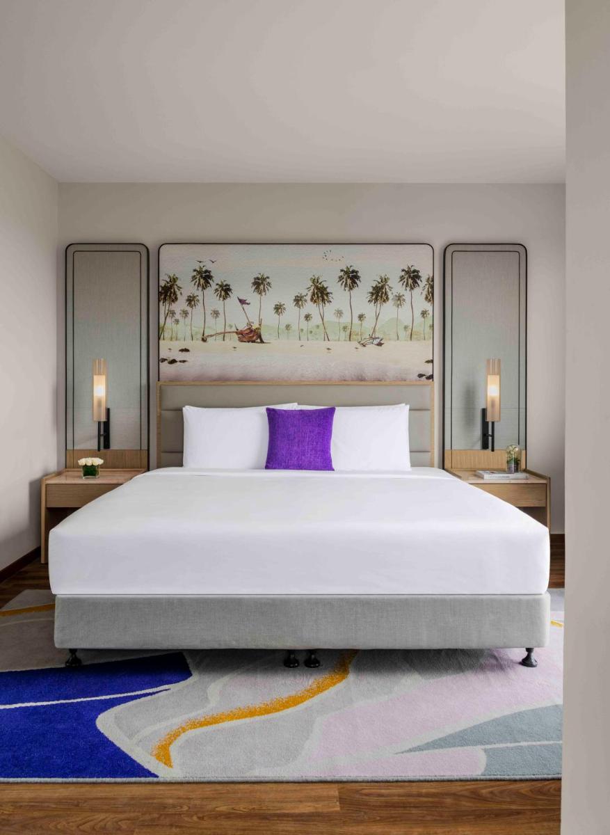 a bedroom with a large white bed with a purple pillow at Vivanta Goa, Miramar in Panaji a bedroom with a large white bed with a purple pillow at Vivanta Goa, Miramar in Panaji