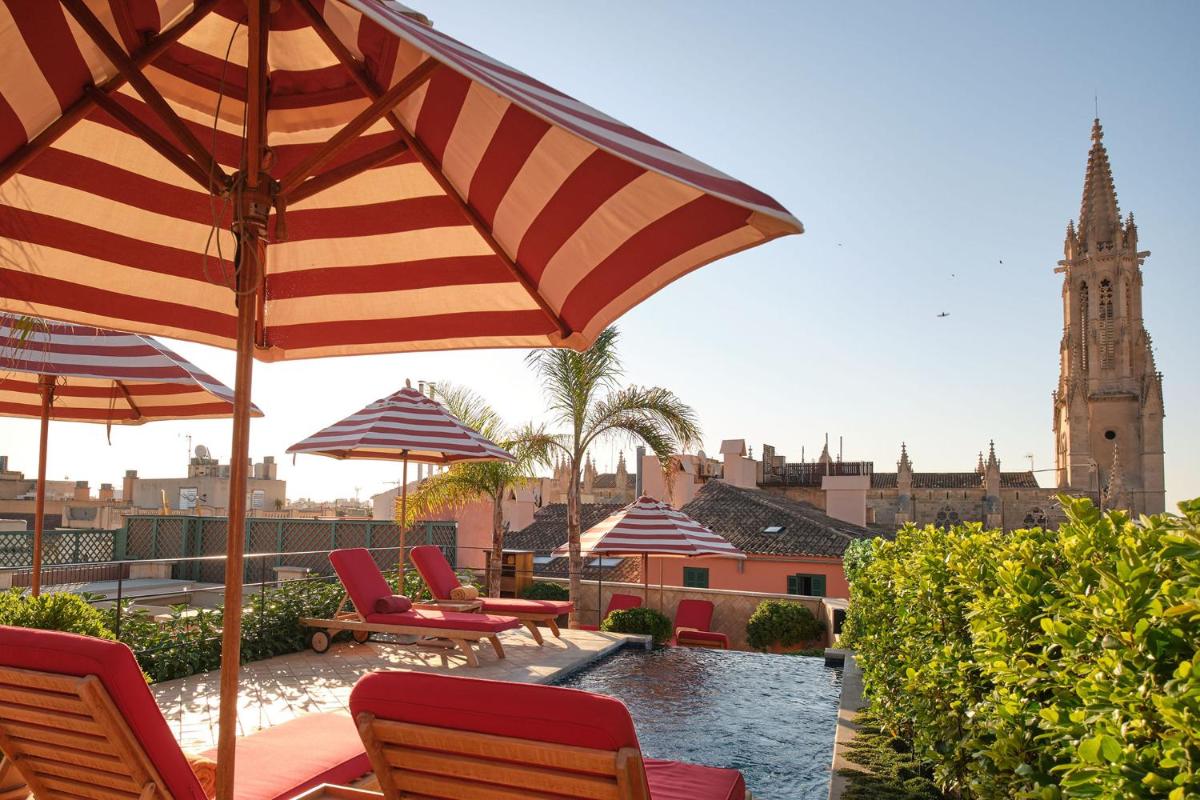 un patio con sillas y sombrillas y una torre de reloj en Hotel Cappuccino - Palma, en Palma de Mallorca