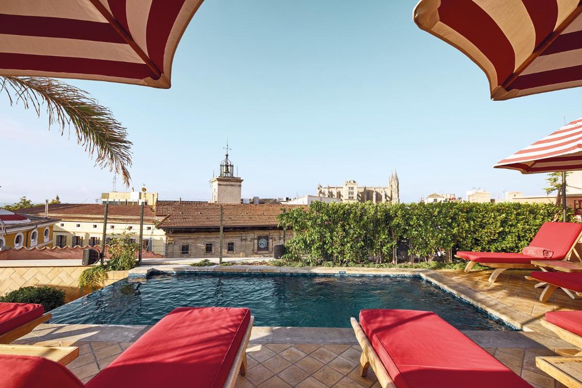 una piscina con sillas rojas y sombrilla en Hotel Cappuccino - Palma, en Palma de Mallorca