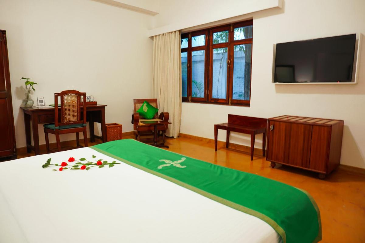 a bedroom with a bed with a green blanket on it at Saraca Hotel Lucknow in Lucknow