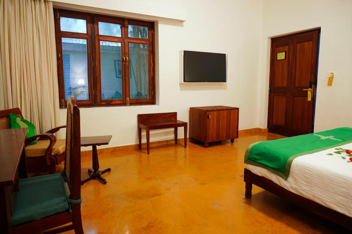 a bedroom with a bed and a tv and a chair at Saraca Hotel Lucknow in Lucknow