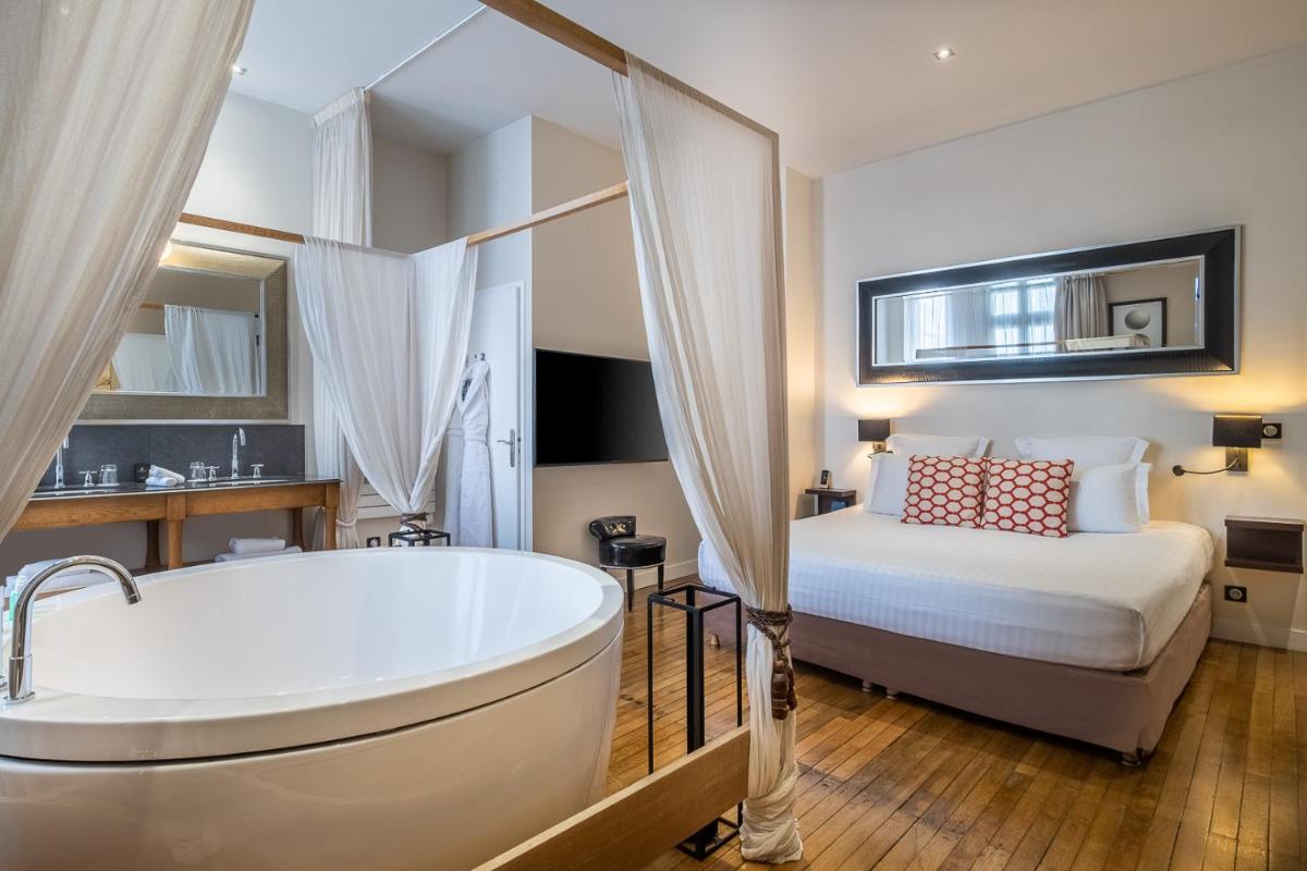 La salle de bains est pourvue d'une baignoire et d'un lit. dans l'établissement Le Boutique Hotel & Spa, à Bordeaux