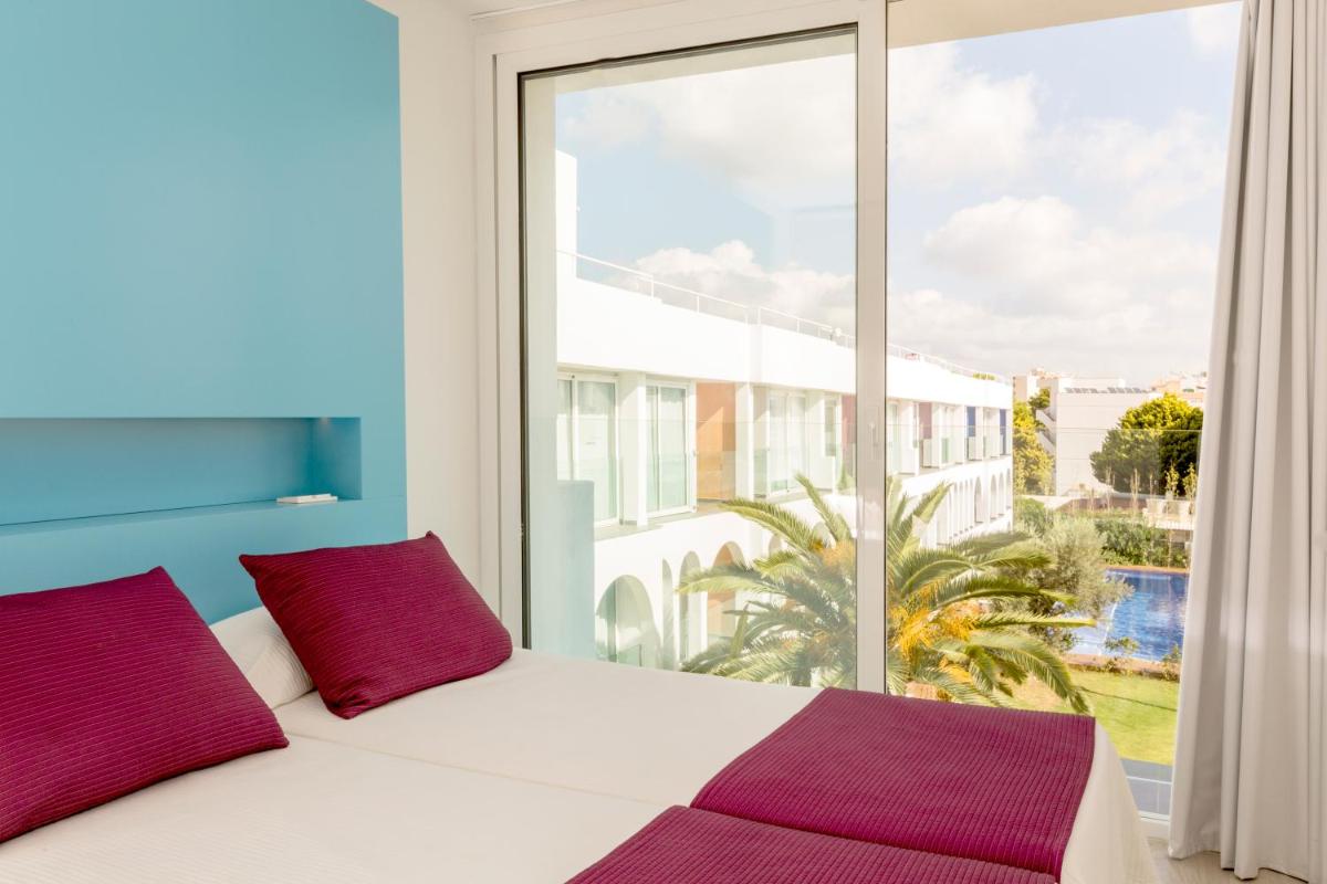 Un dormitorio con una cama y una ventana grande. en Ebano Hotel Apartments & Spa, en Playa d'en Bossa