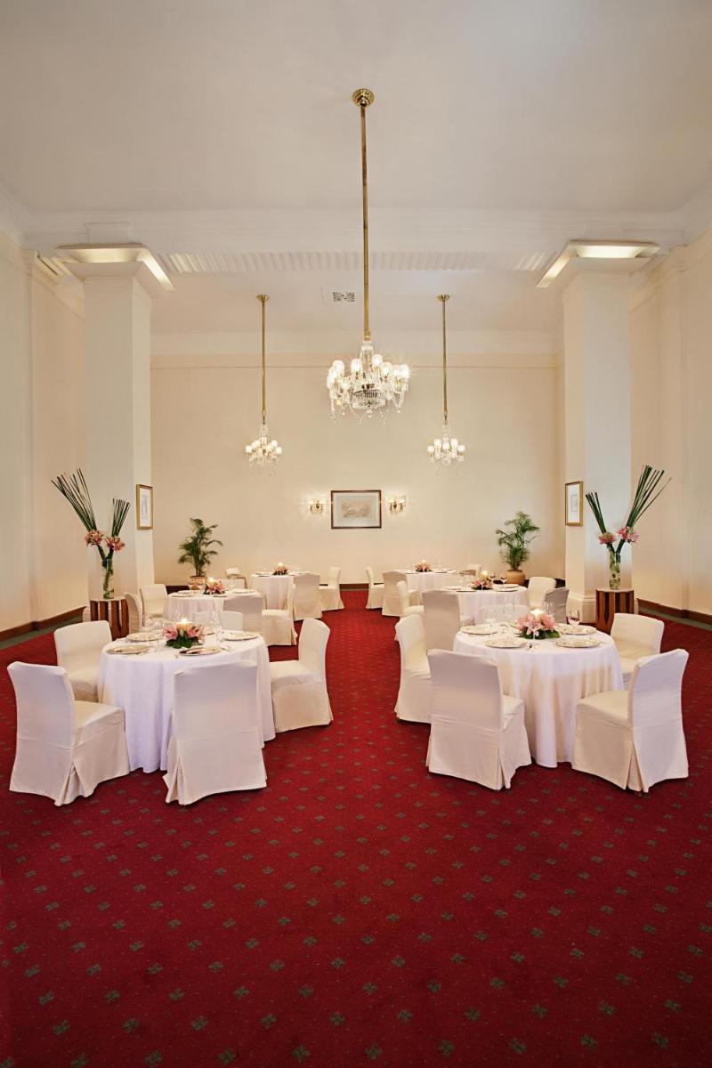 a banquet room with white tables and white chairs at Maidens Hotel New Delhi in New Delhi