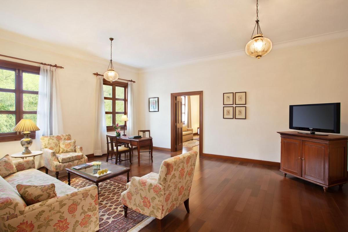 a living room with a couch and a tv at Maidens Hotel New Delhi in New Delhi