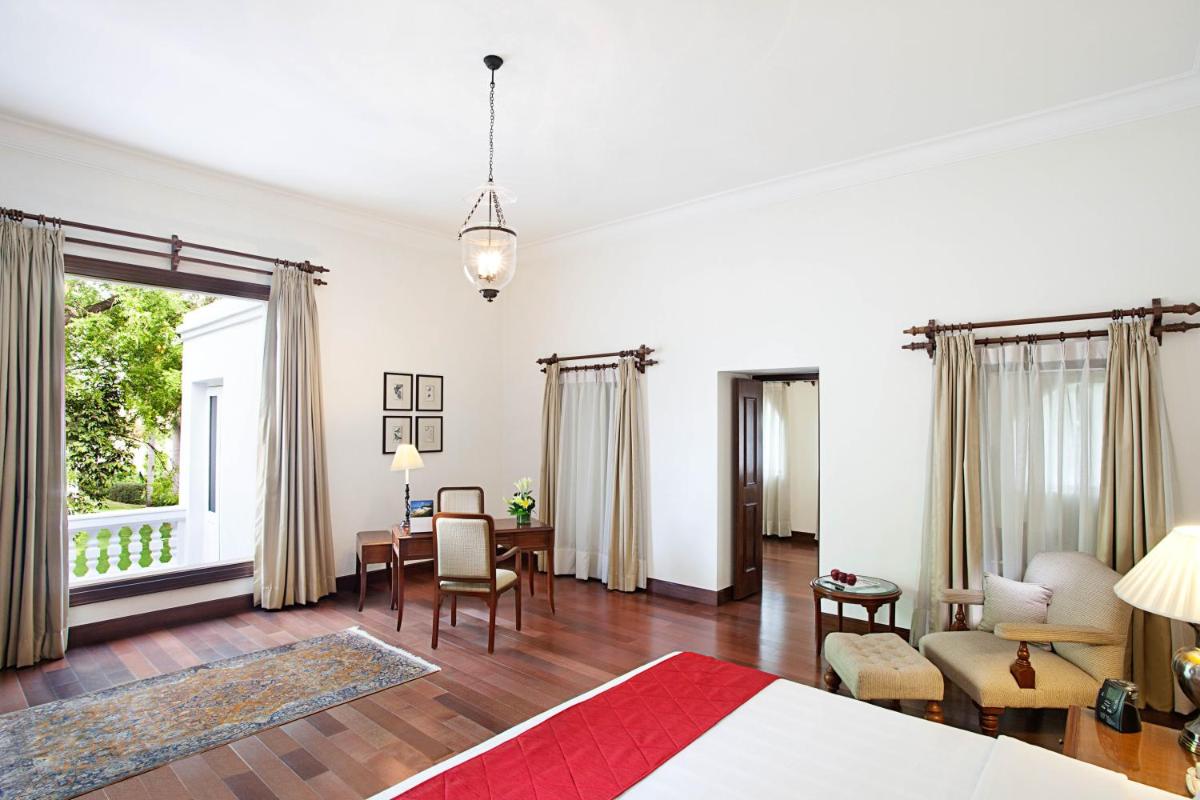 a bedroom with a bed and a table and chairs at Maidens Hotel New Delhi in New Delhi