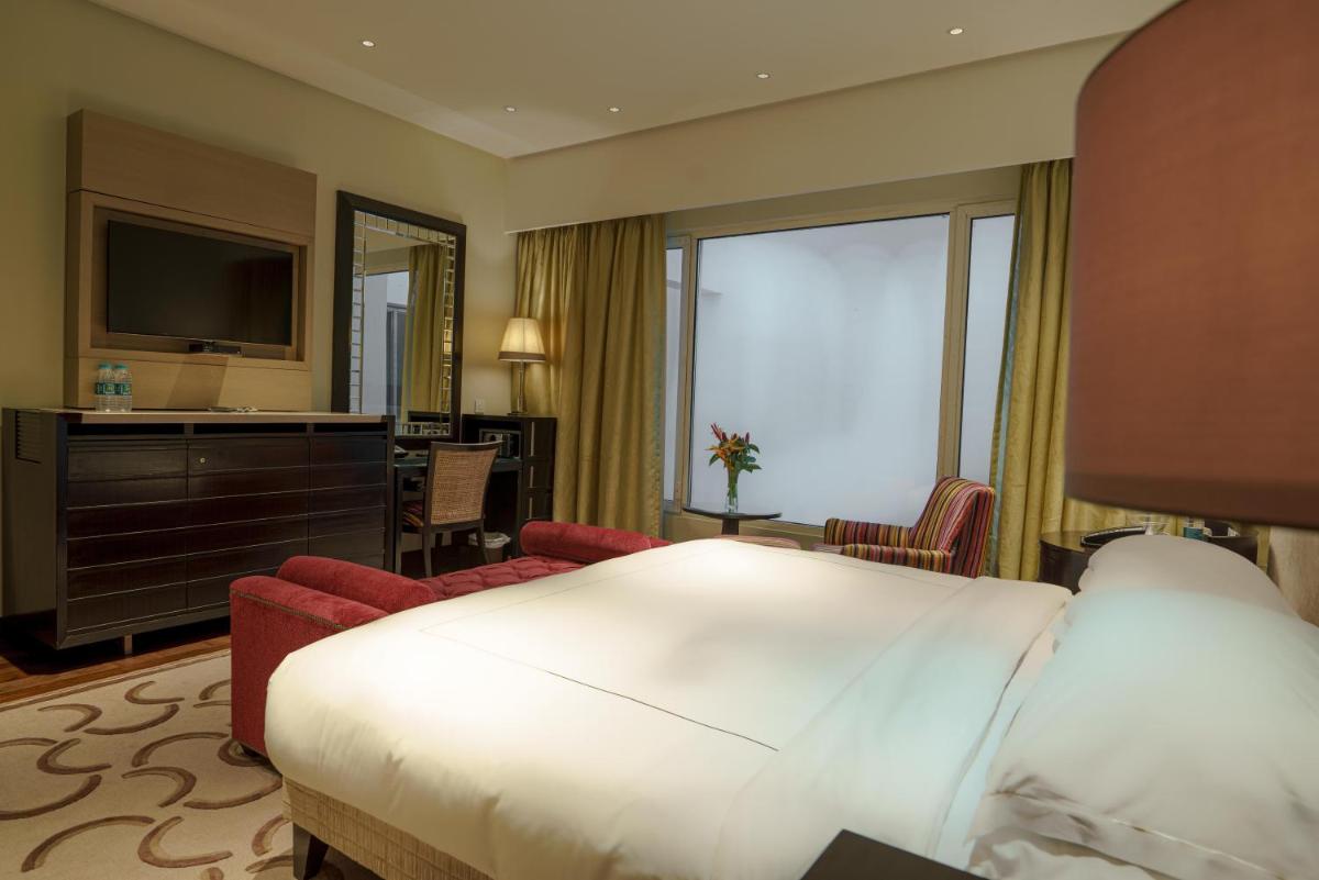 a hotel room with a large bed and a television at Taj Santacruz in Mumbai