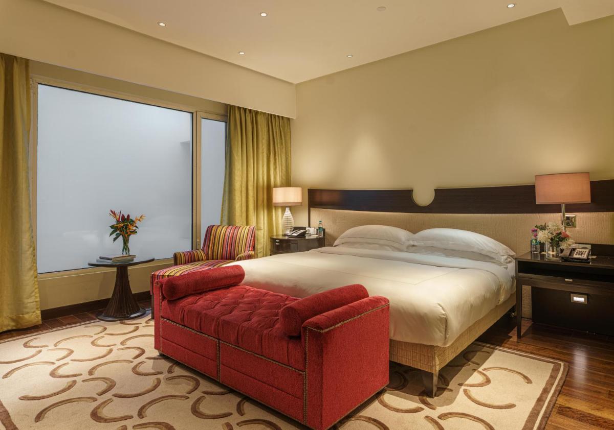 a bedroom with a large bed and a red couch at Taj Santacruz in Mumbai