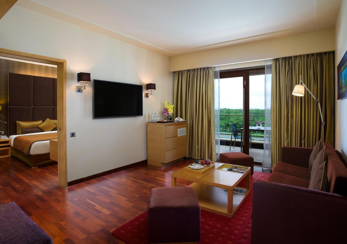 a living room with a couch and a television in a hotel room at Novotel Hyderabad Airport in Hyderabad