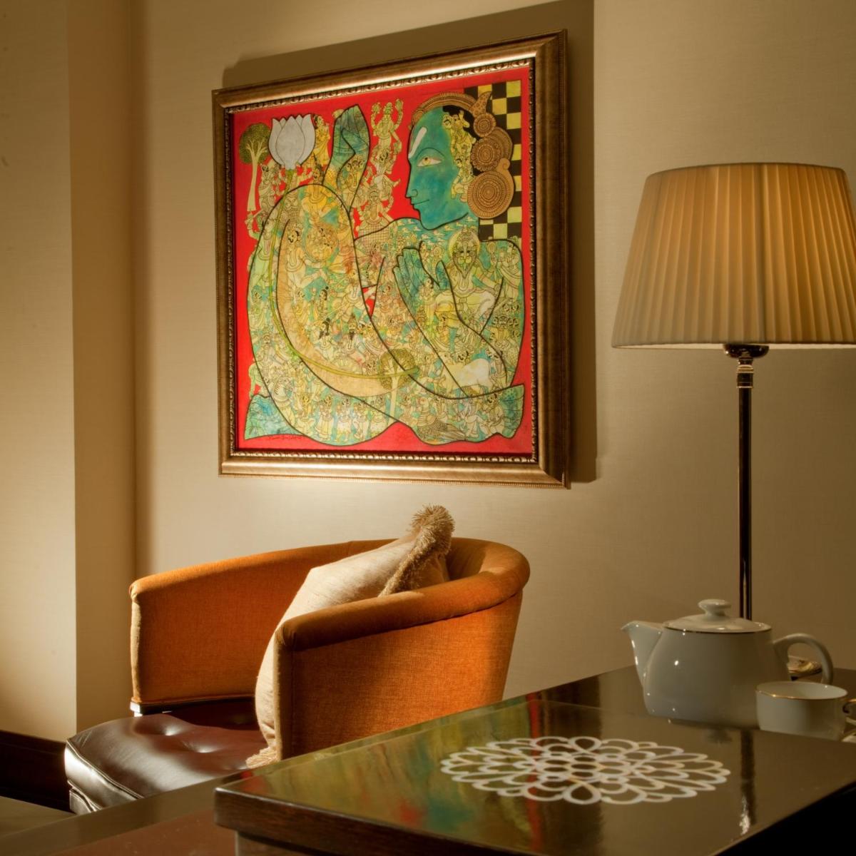a living room with a table and a painting on the wall at The Leela Palace Chennai in Chennai a living room with a table and a painting on the wall at The Leela Palace Chennai in Chennai