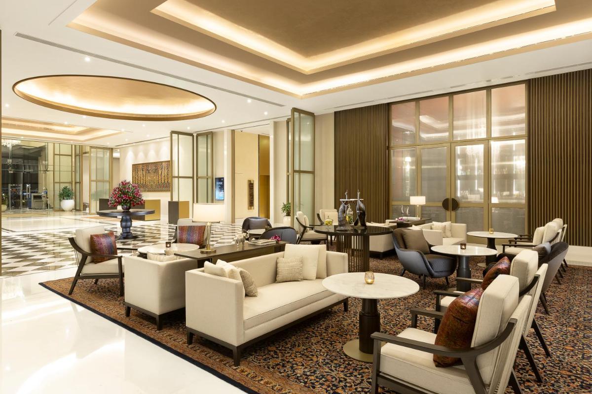 a hotel lobby with couches and tables and chairs at The Leela Bhartiya City Bengaluru in Bengaluru a hotel lobby with couches and tables and chairs at The Leela Bhartiya City Bengaluru in Bengaluru