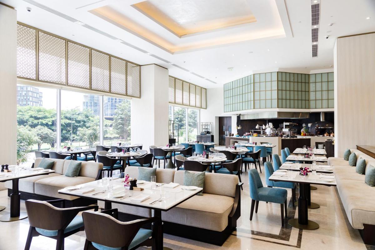 a restaurant with tables and chairs and windows at The Leela Bhartiya City Bengaluru in Bengaluru a restaurant with tables and chairs and windows at The Leela Bhartiya City Bengaluru in Bengaluru