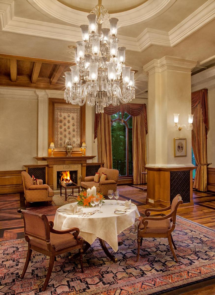 a living room with a table and a chandelier at Wildflower Hall, An Oberoi Resort, Shimla in Shimla