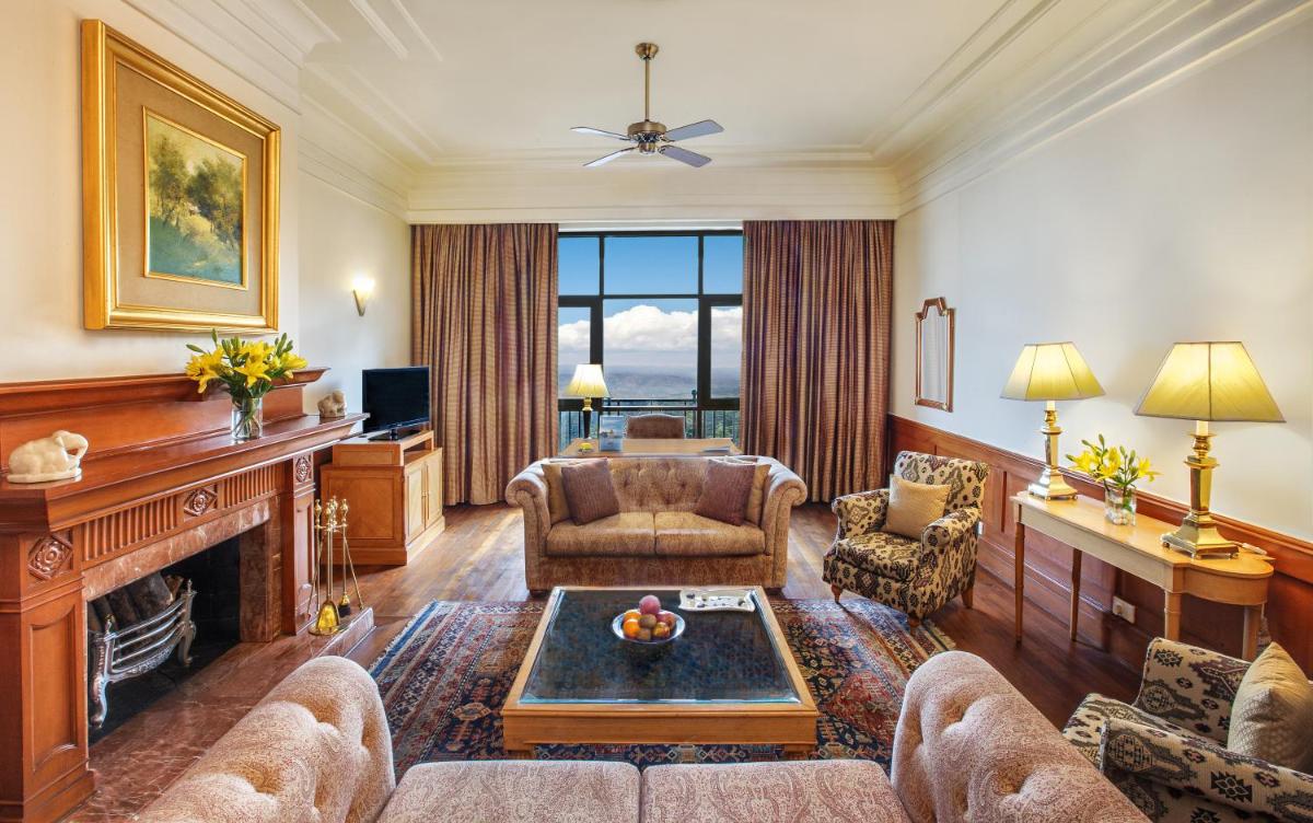 a living room with a couch and a fireplace at Wildflower Hall, An Oberoi Resort, Shimla in Shimla