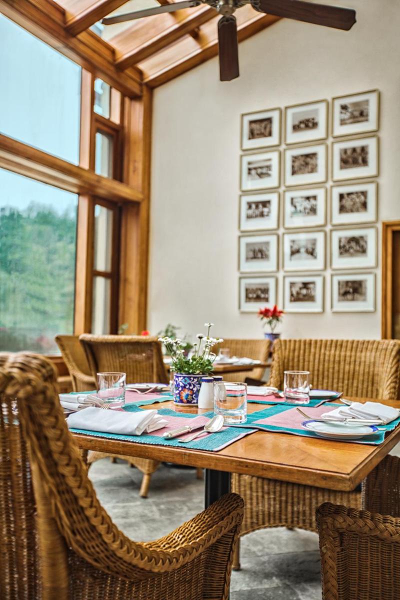a dining room with a wooden table and chairs at Wildflower Hall, An Oberoi Resort, Shimla in Shimla