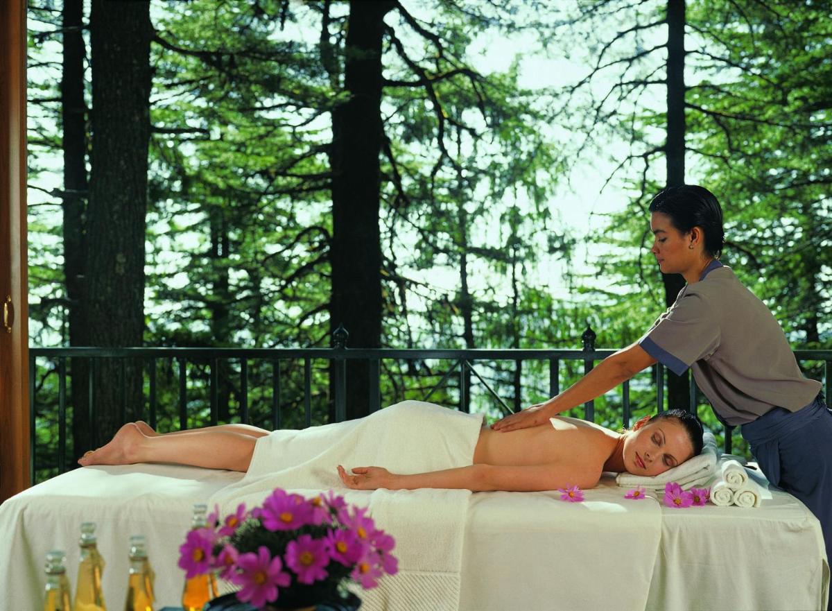 a man giving a woman a massage on a bed at Wildflower Hall, An Oberoi Resort, Shimla in Shimla
