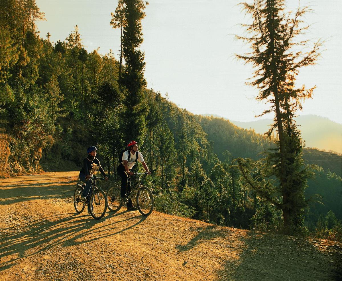 two people riding bikes on a dirt road at Wildflower Hall, An Oberoi Resort, Shimla in Shimla